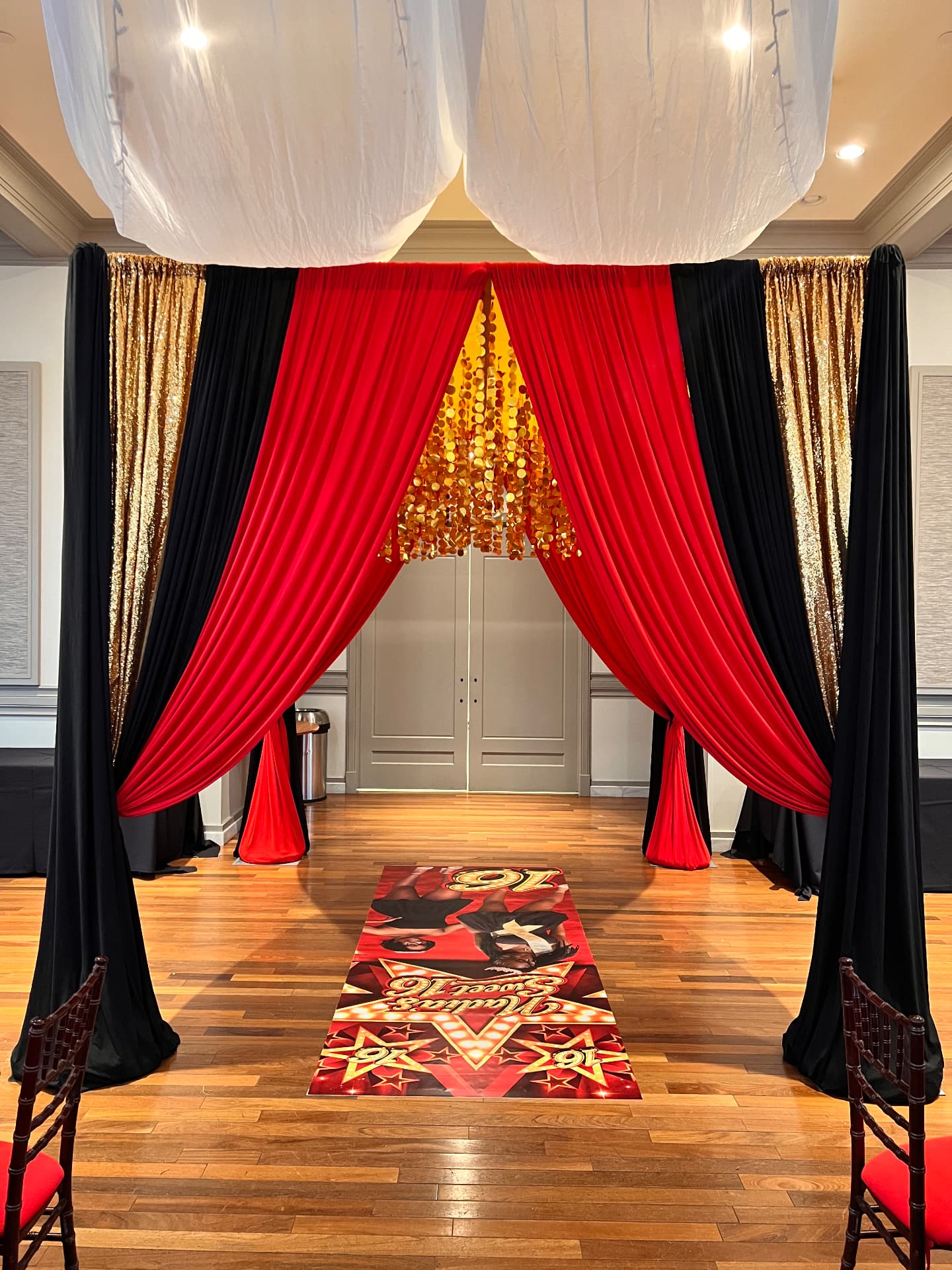 Sweet 16 draped entrance in red, black and gold with custom floor graphic