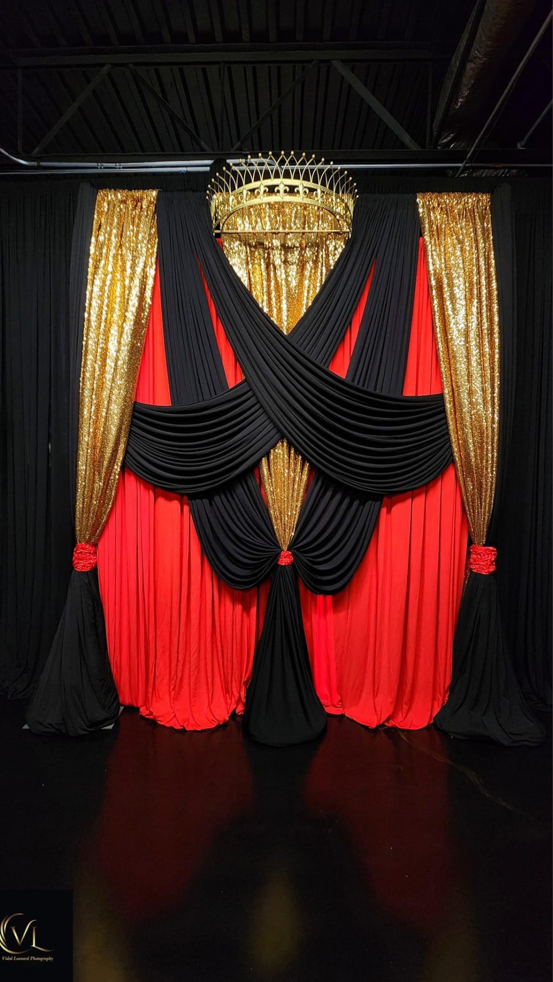 Black, red and gold sequin criss-cross draped backdrop with gold crown chandelier