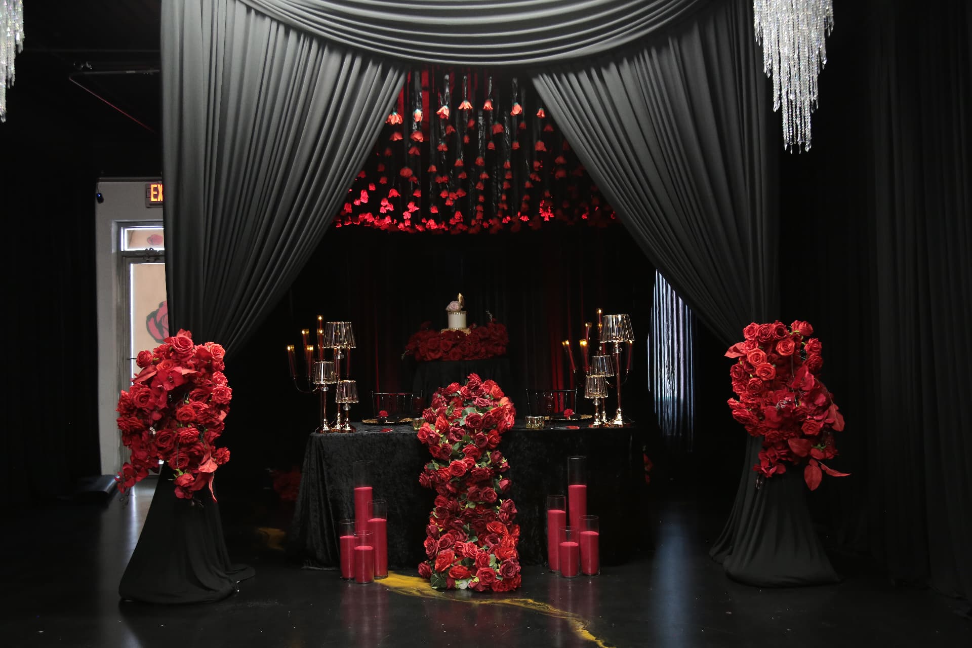 Black draped cabana with cascading red roses, candlelight and crystal chandeliers