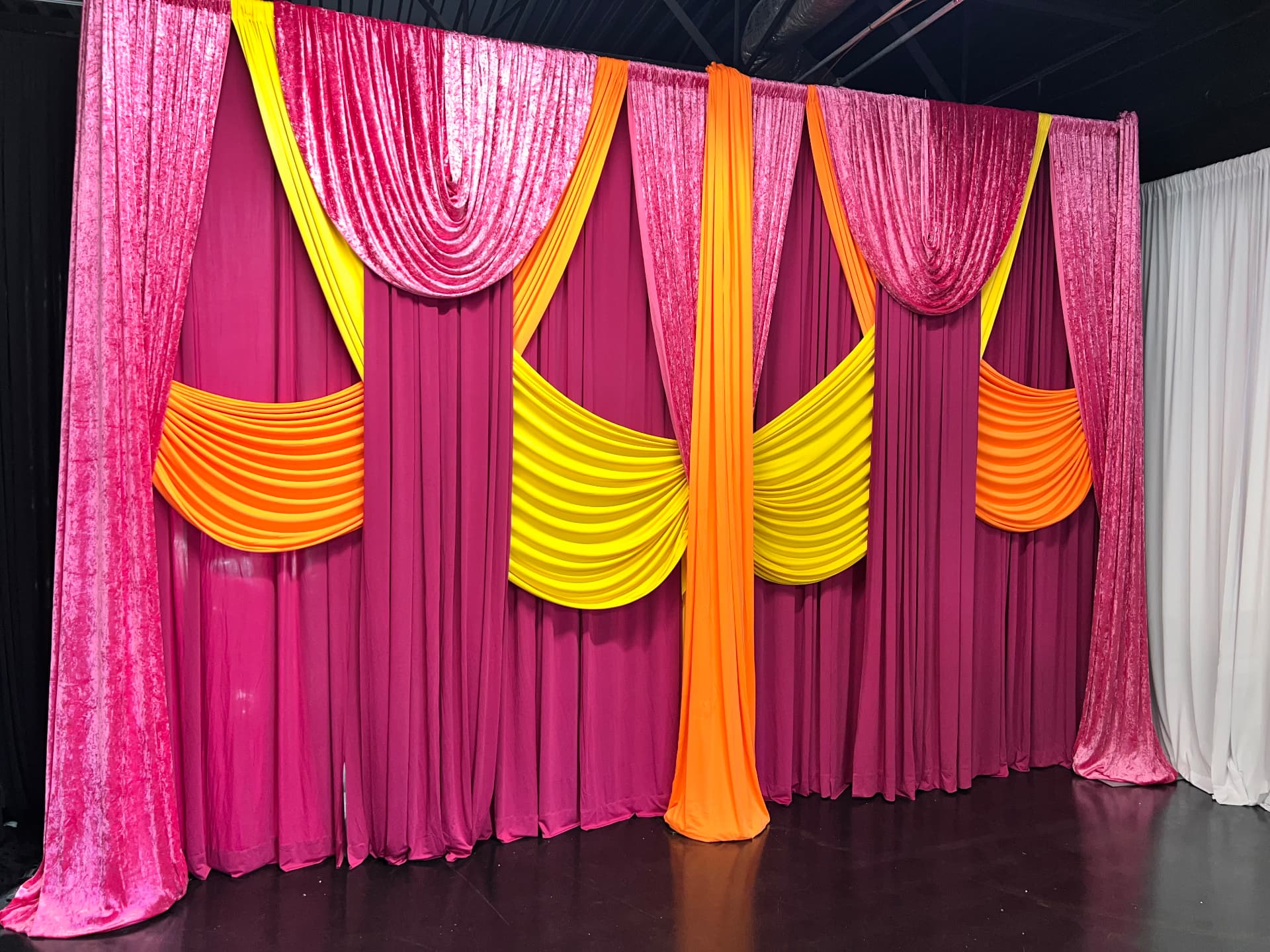 Fuchsia, orange and yellow layered draping backdrop wall