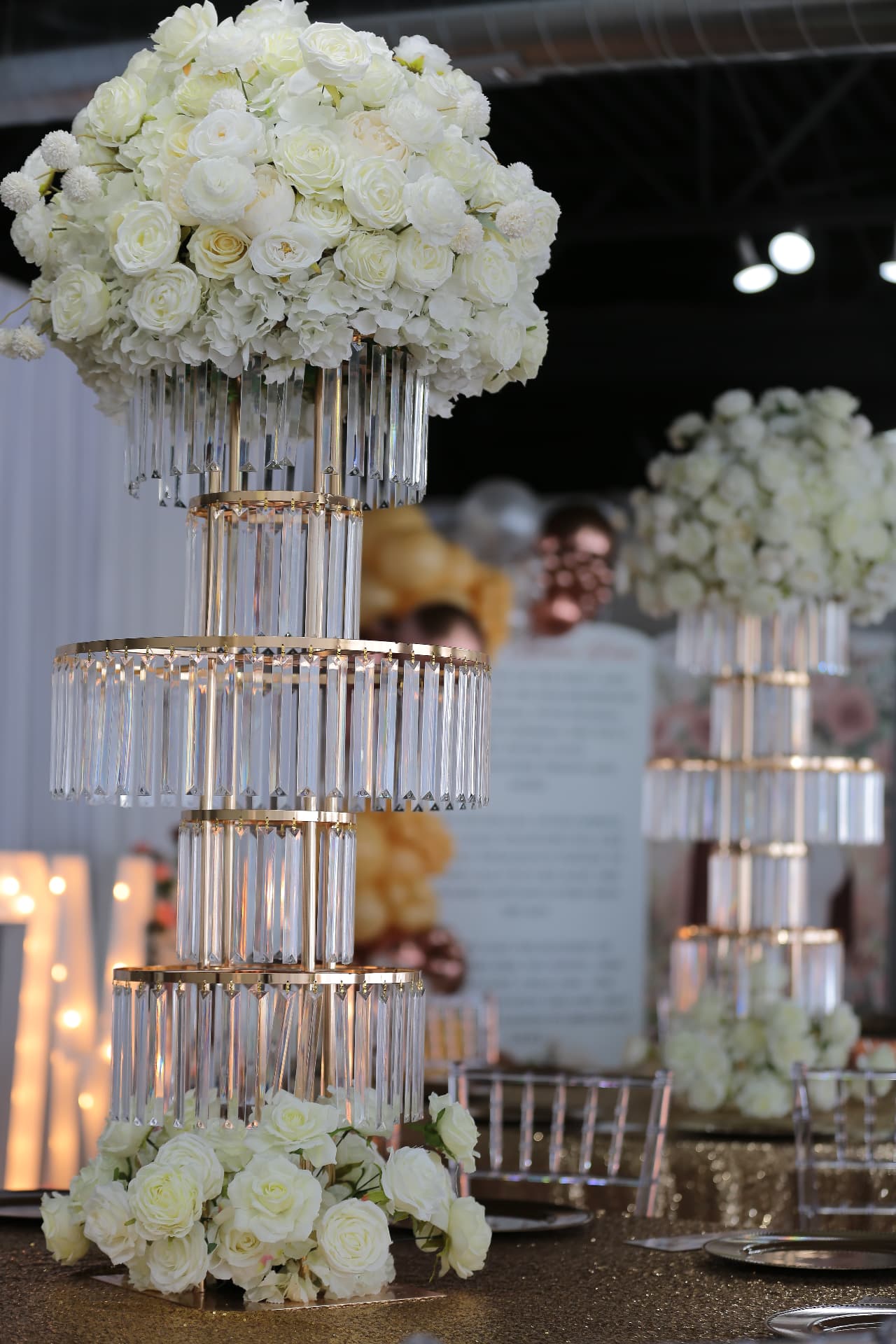 Tall crystal centerpiece with white roses on a mirrored tablescape